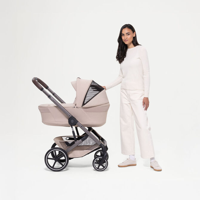 A woman standing next to two Balios S Lux strollers, showcasing the sun canopy of both.