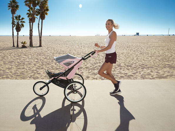 Woman jogging on the beach with a Zeno electric stroller.