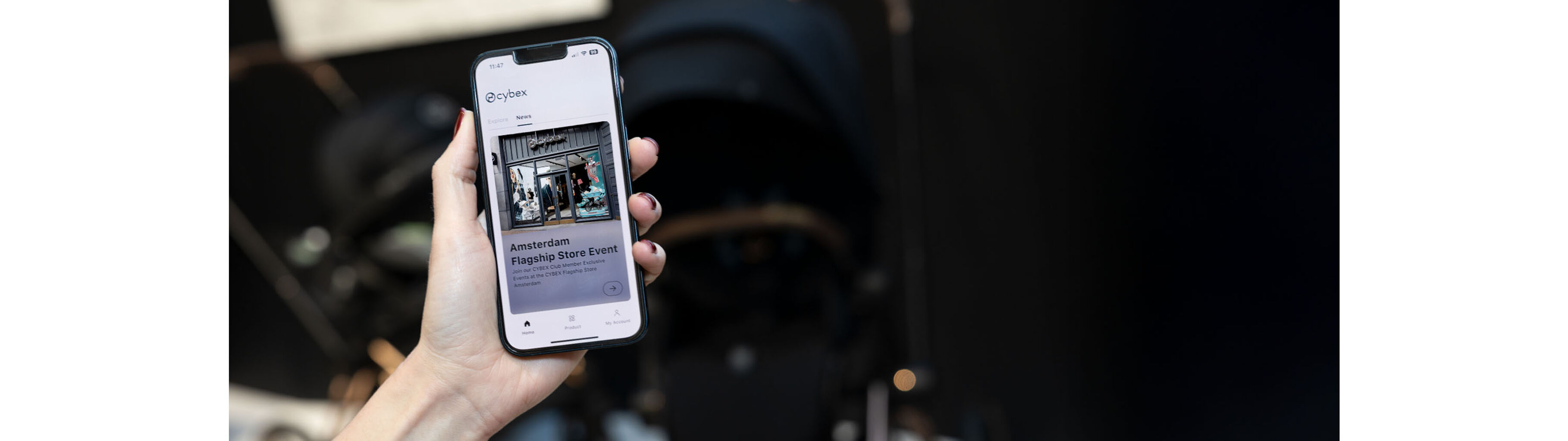 A woman with nail polish holding a phone into the camera. On the phone screen, it says "Amsterdam Flagship Store Event"