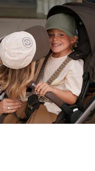 A mother kisses her son's cheek who is sitting in a CYBEX buggy.