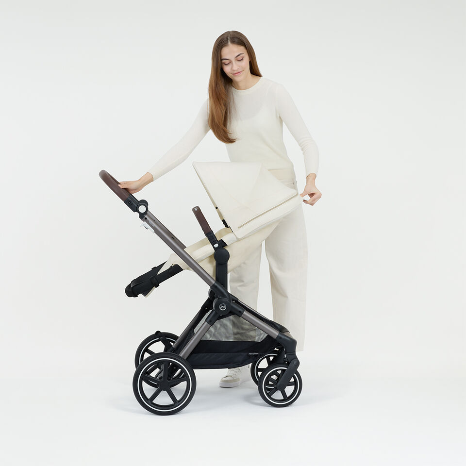 A woman bringing her Eos Lux stroller into an ergonomic lie-flat position.