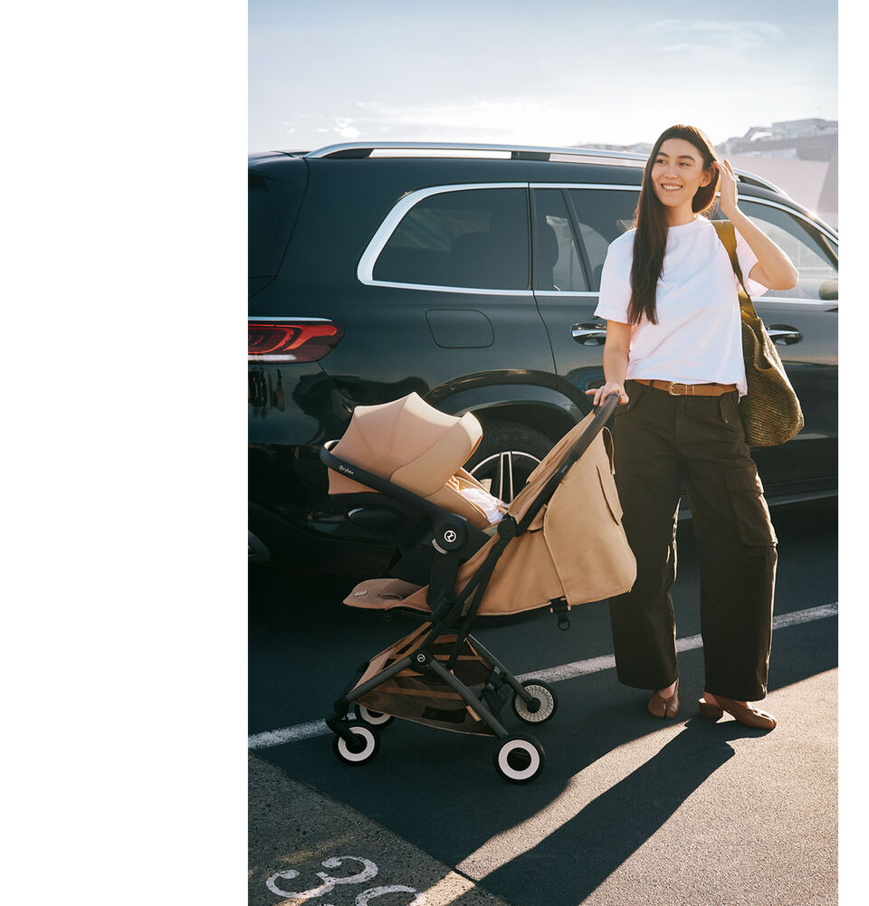 Woman using Orfeo with infant car seat attached next to parked car