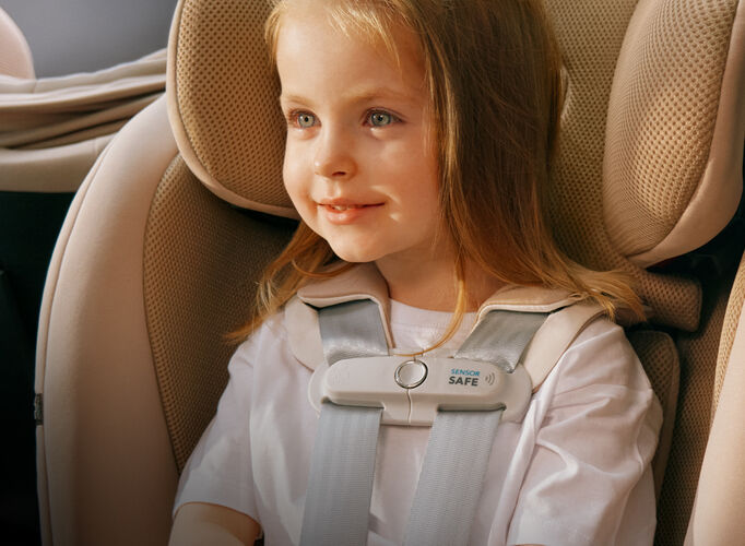 Close-up of a little girl in a CYBEX car seat, a SensorSafe clip attached to the harness.