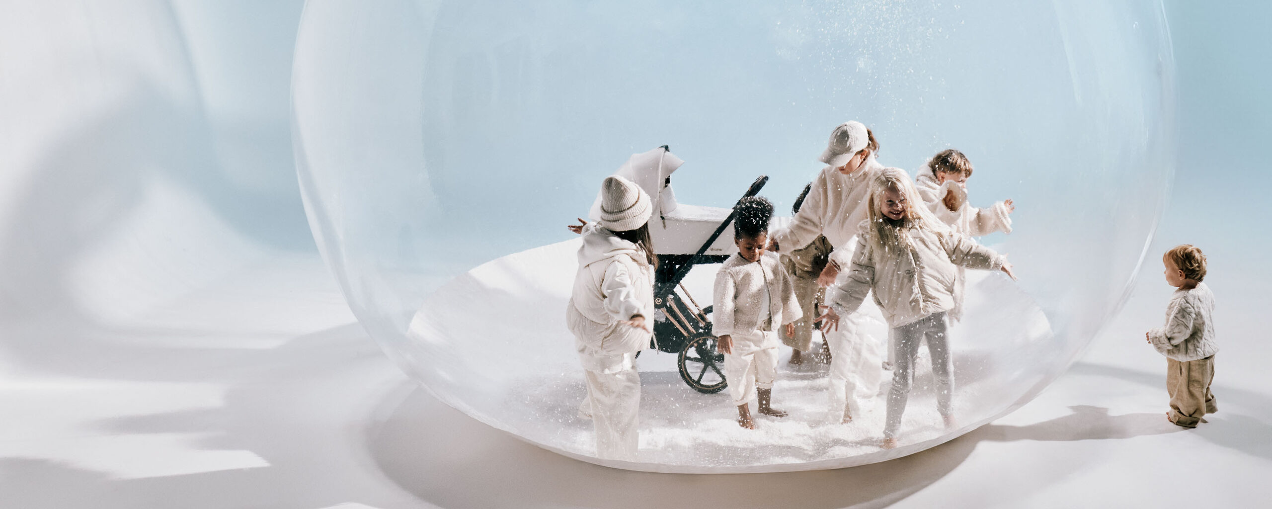 Six children playing in a makeshift globe that looks like a snow globe with a CYBEX Priam stroller.
