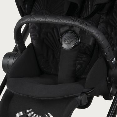 Afbeelding van de CYBEX Platinum Mios - La Parisienne Stroller, met de nadruk op de functie Gordelsysteem met treksluiting.