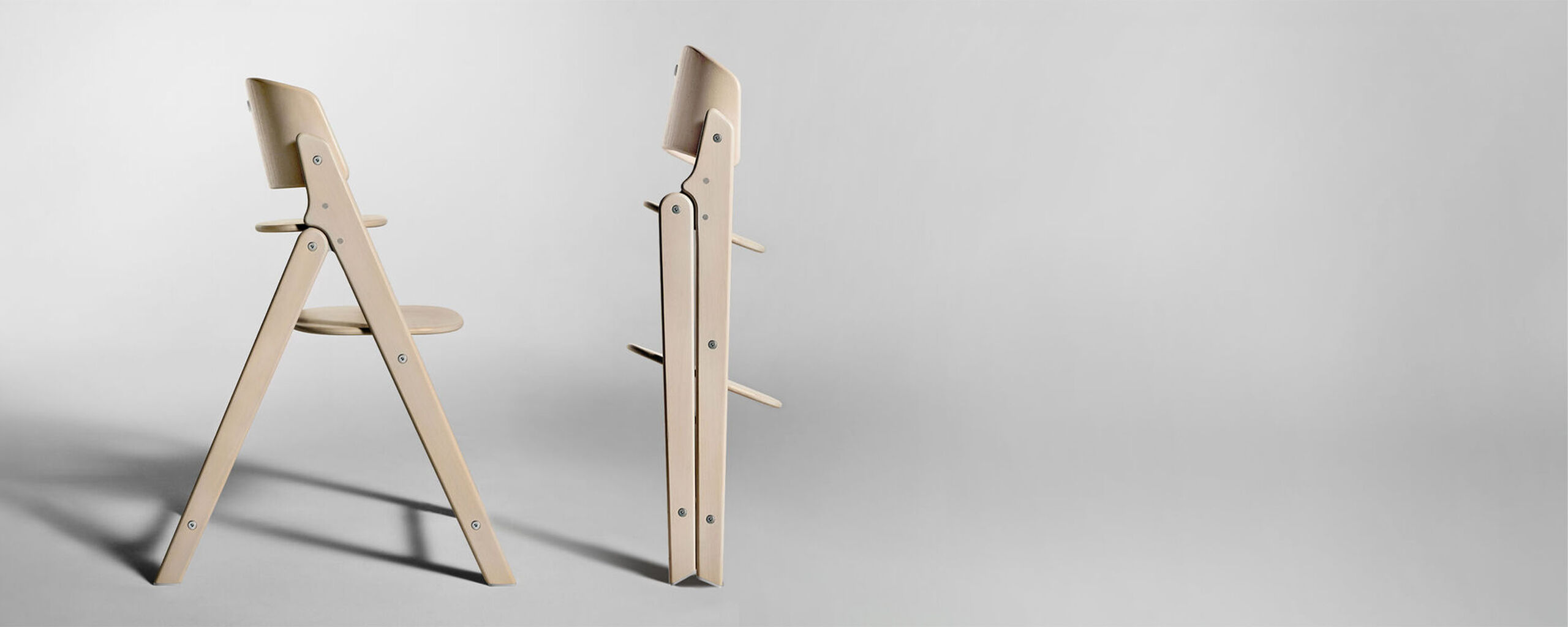 A modern, foldable wooden chair in a light wood tone, shown once open and once folded.