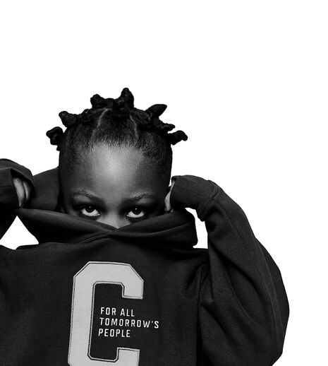 A child hiding half their face in a CYBEX hoodie, looking directly into the camera.