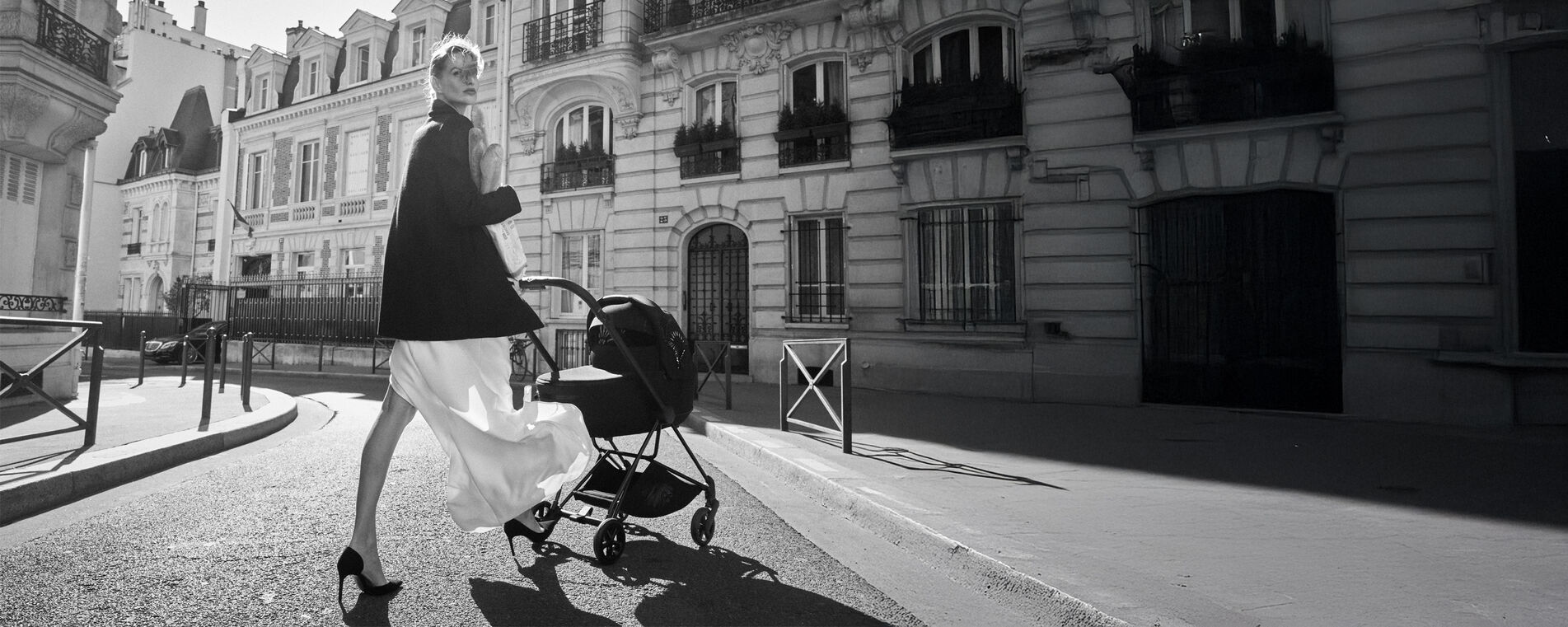 A woman in an elegant outfit with a stroller on a Parisian street