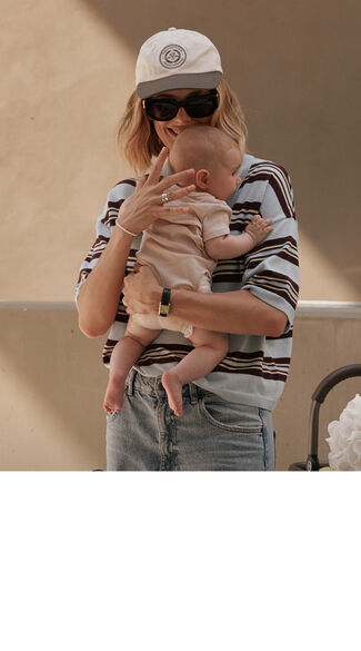 A mother holding her baby close to her chest and smiling.