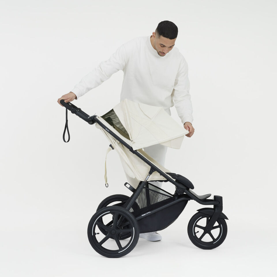 Product shot of a man pulling down the sun canopy of an Avi Spin stroller.