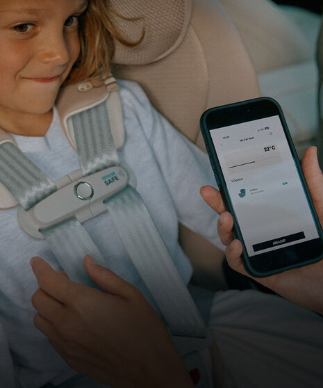 Ein Kind sitzt in einem Kindersitz mit SensorSafe, vor ihm ist ein Smartphone mit der CYBEX-App.
