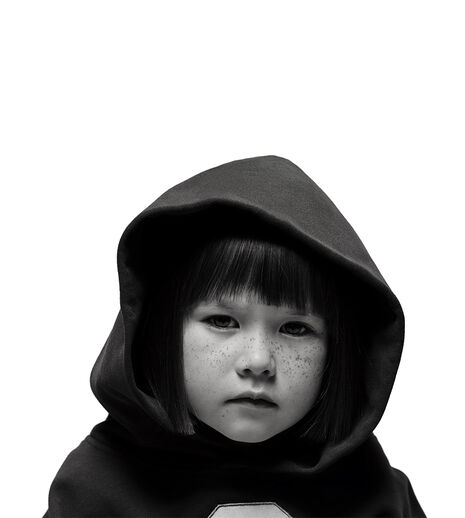 A young girl with freckles looking directly into the camera. She's wearing a hoodie.
