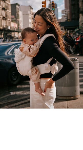 A woman carrying a baby in a CYBEX baby carrier.