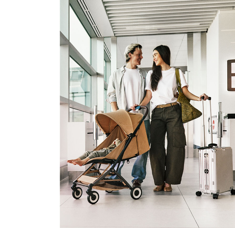 Couple walking through airport with compact Orfeo stroller and child, carrying luggage