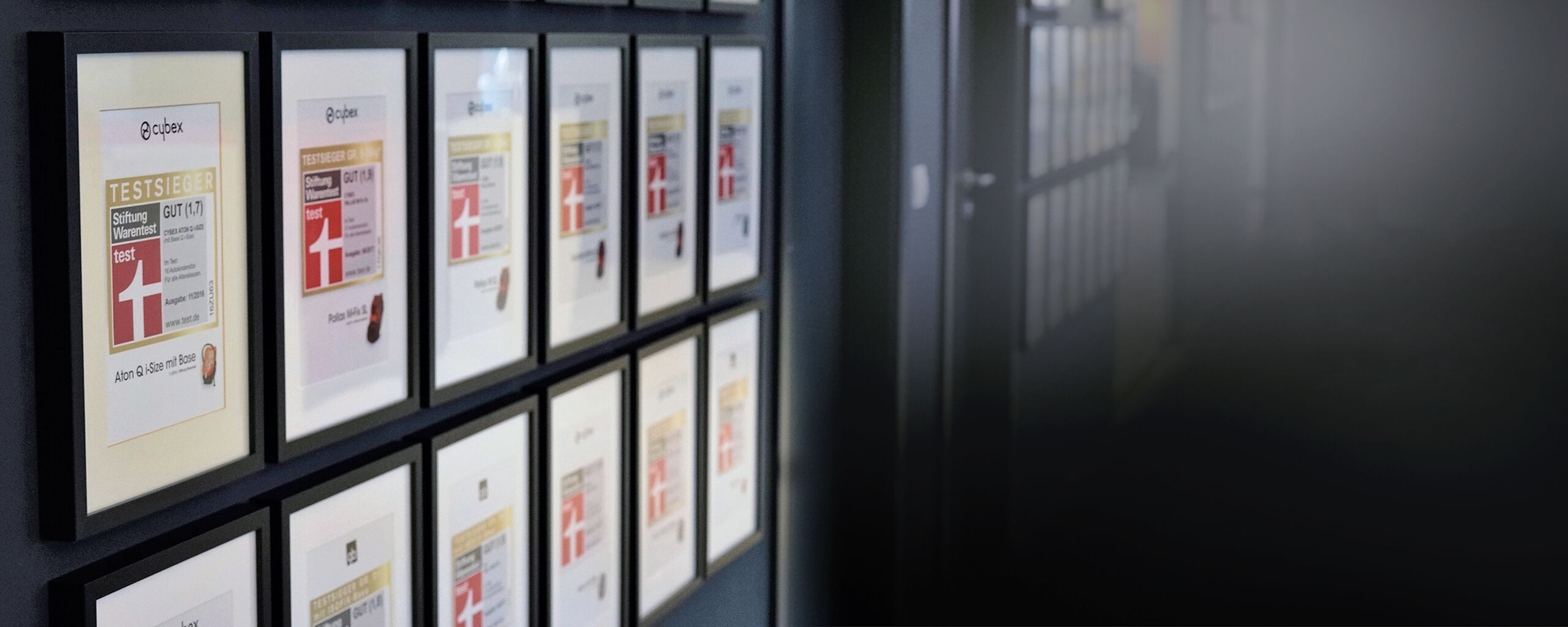 Wall with framed Cybex awards, including test winner certificates from Stiftung Warentest.