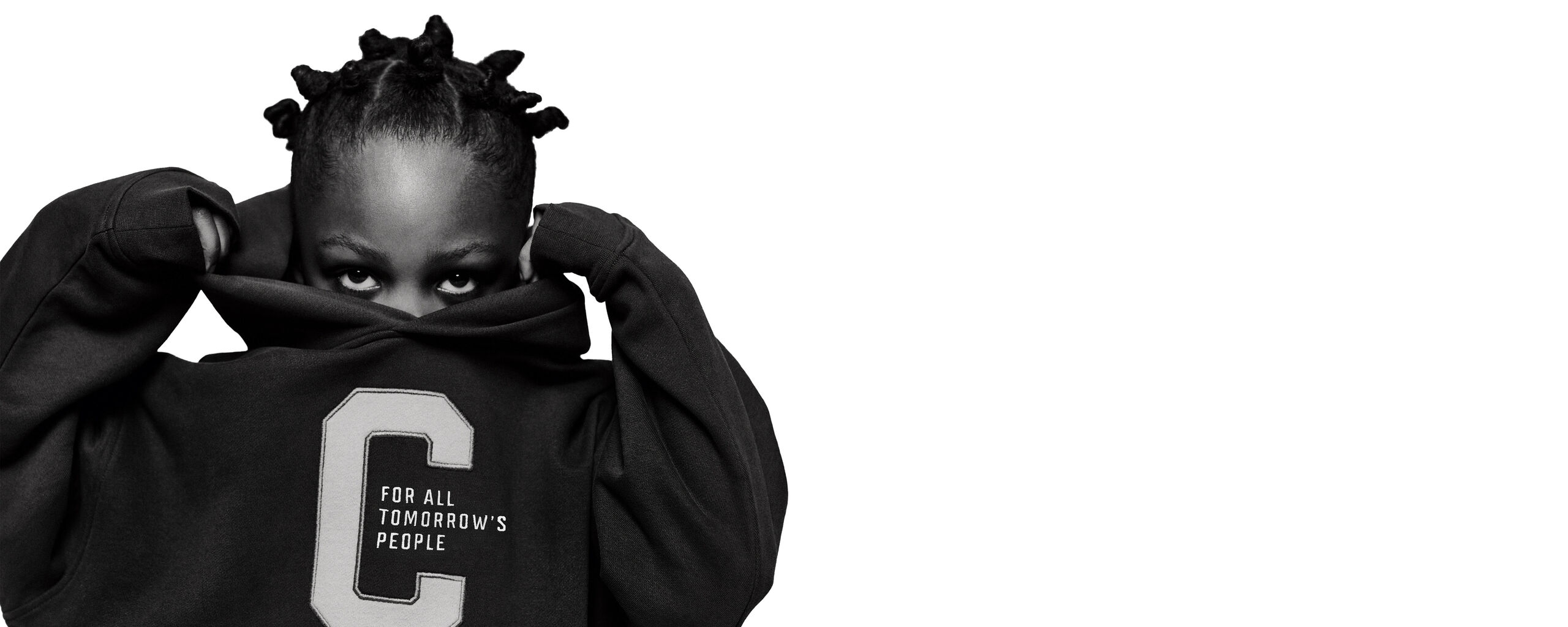 Adult model pulling up the collar of an oversized black CYBEX sweatshirt in a white studio setting.