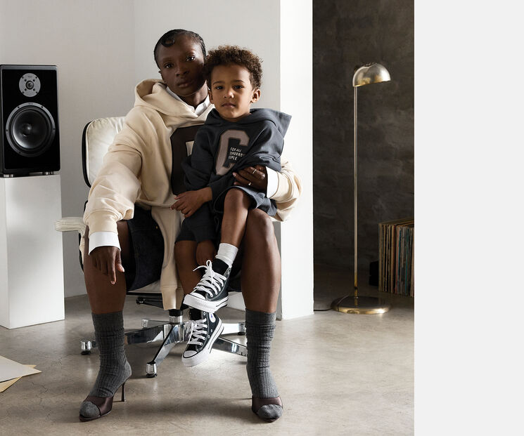 A mother sits on a chair, her son on one leg. Both look directly into the camera.