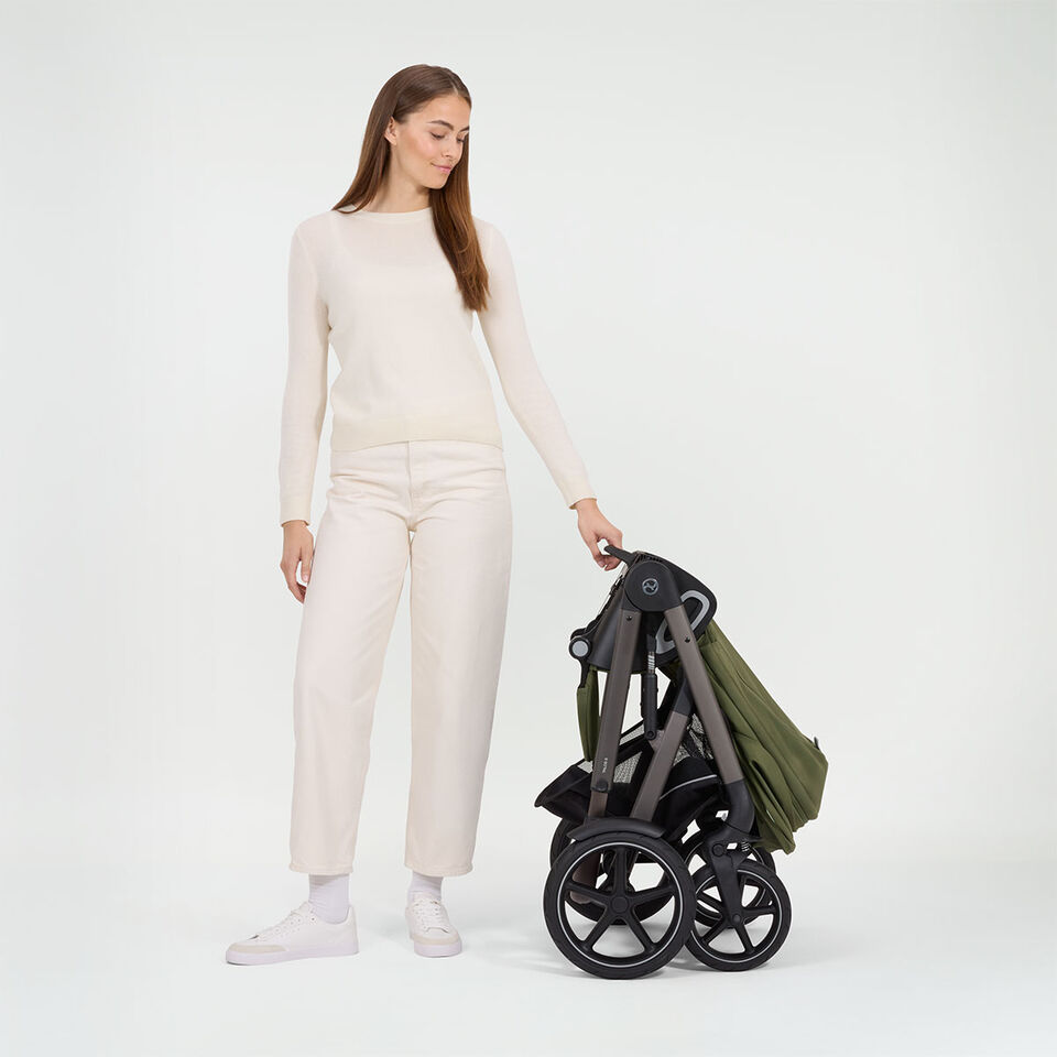 A woman standing next to a folded up Talos S Lux stroller.