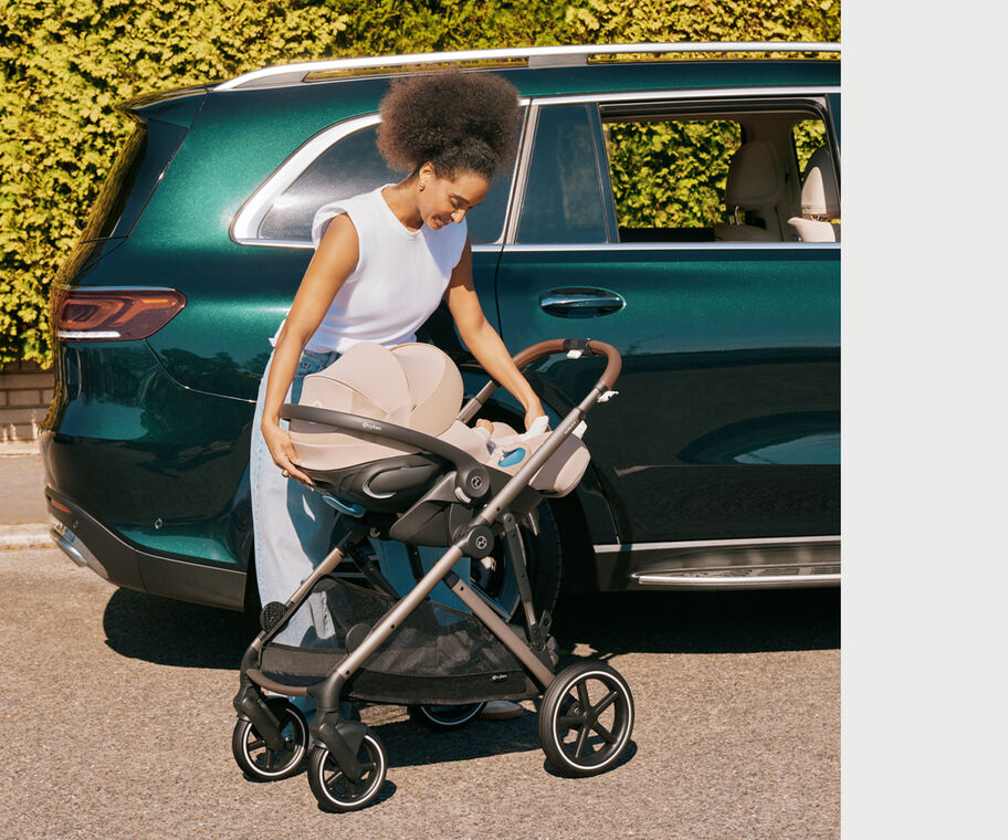 A mother reclining the Cloud G Pro infant car seat next to her car while the car seat is attached to the stroller.