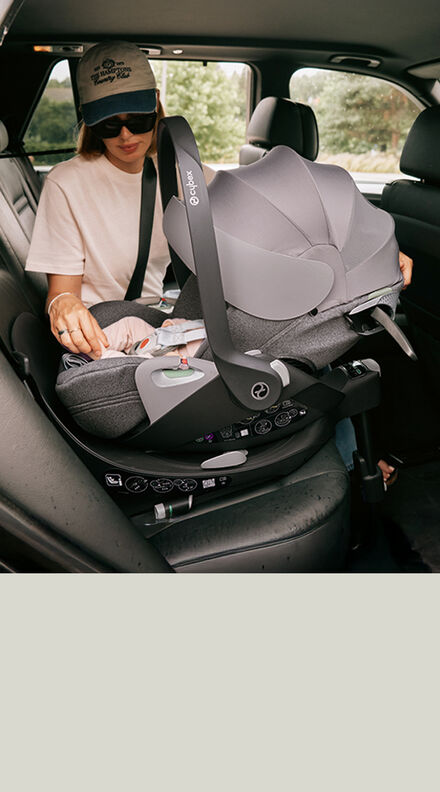 A mother sitting in the back of a car next to her child in a Cloud T infant car seat.