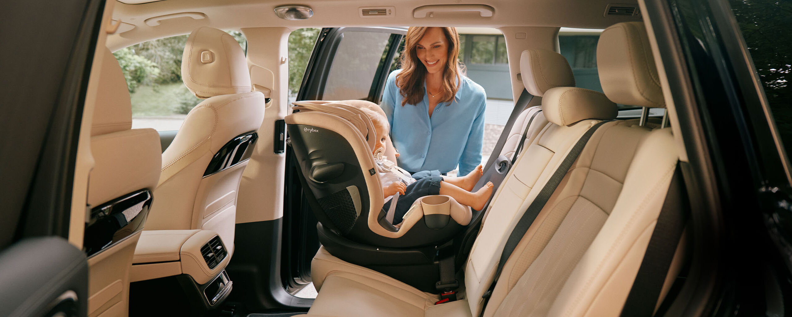 A mother smiling at her baby in a Callisto G 360 rotating convertible car seat installed in the back seat of a car.