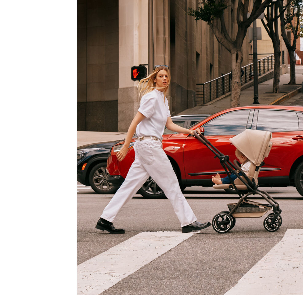 A mother pushing her Eezy S Twist +2 buggy over a street, two cars behind her.