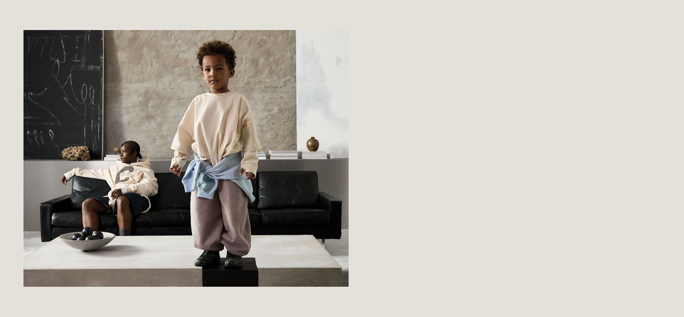 A child standing on top of a table, the mother sitting behind him. Both are wearing CYBEX apparel.