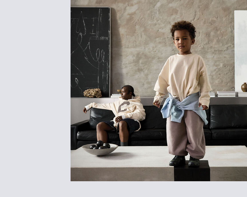 Two children wearing CYBEX apparel in a modern living room.