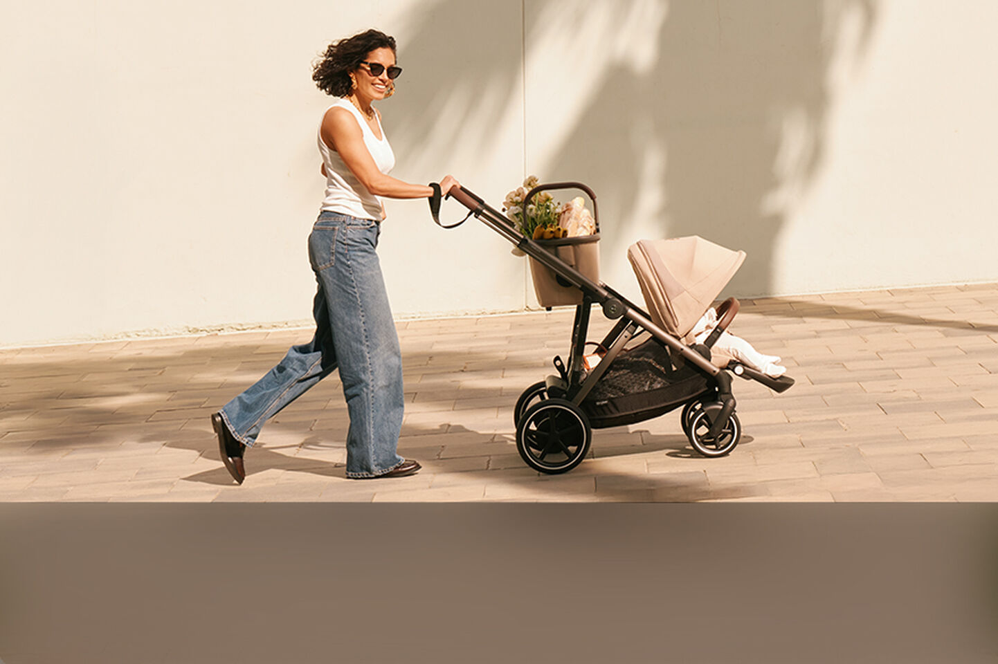 A woman pushing a Gazelle S stroller with a seat pack and a basket.