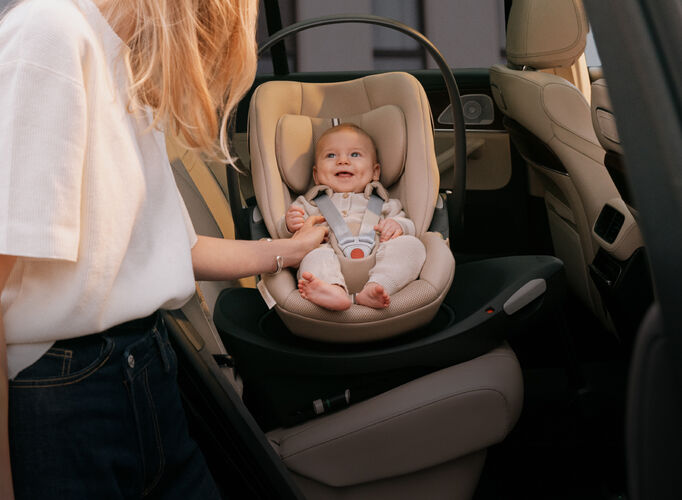 A baby in a Cloud G infant car seat, smiling up at his mother.