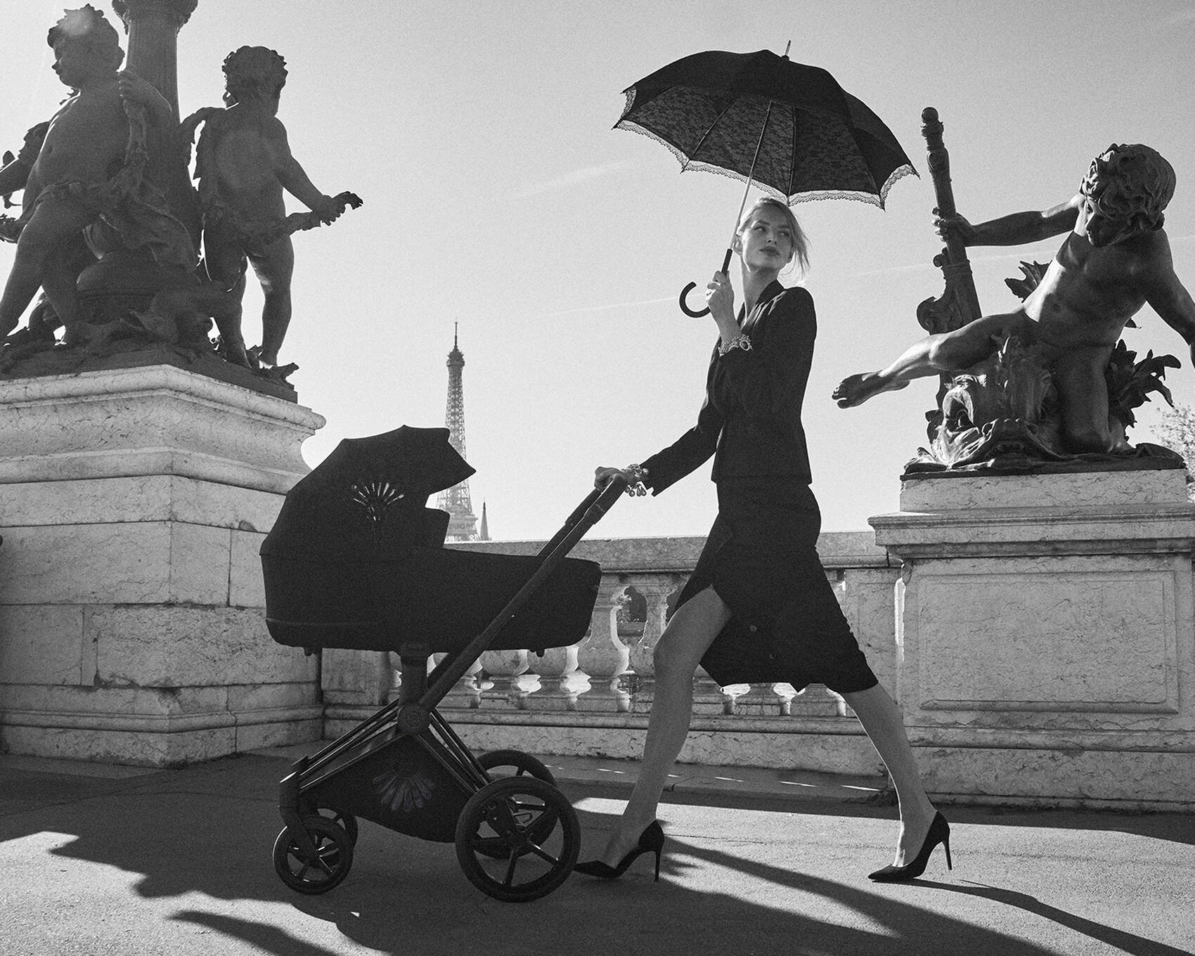 Frau, die mit einem La Parisienne Priam und einem Sonnenschirm spazieren geht