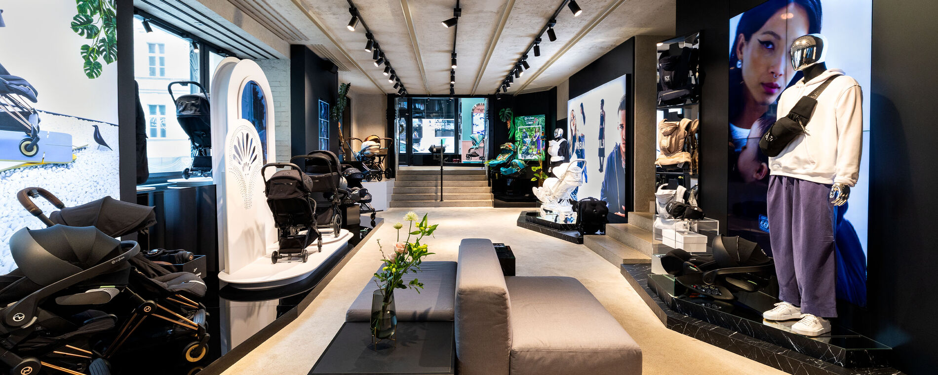 CYBEX Flagship Store Prague. A variety of pushchairs and car seats in a large space, a couch in the center.