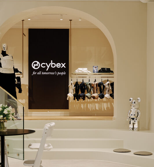 Stairs leading up to a rack full of CYBEX carriers and a picture with the CYBEX logo and slogan.