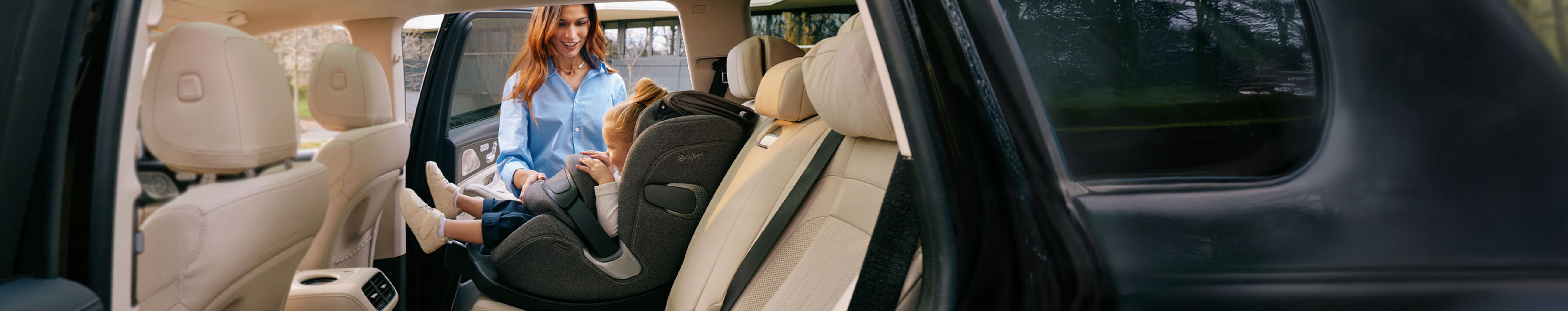 A parent placing a child into a Cybex car seat inside a vehicle, emphasizing safety and comfort.