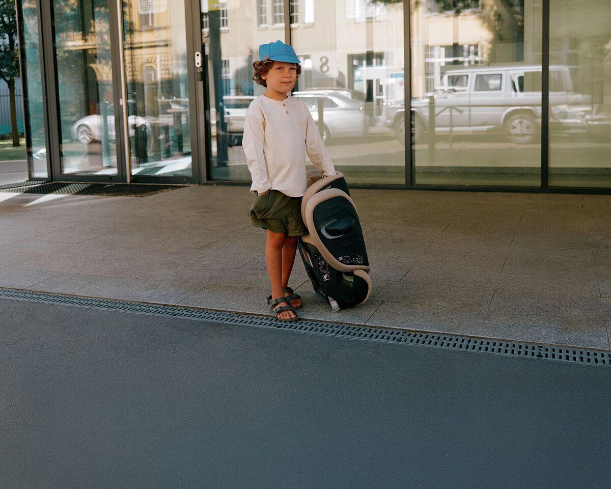 A young boy standing at the side of a street with a folded up Solution G2 next to him.