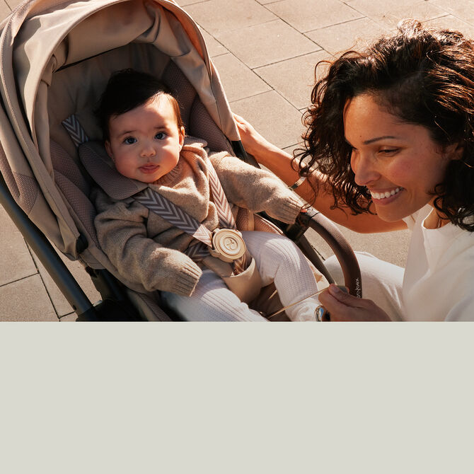 A mother kneeling in front of her CYBEX lightweight stroller with her toddler inside. It reads !10% Voucher Code Off Gold"
