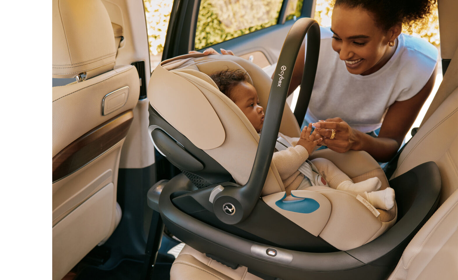 A mother leaning down to her child that is sitting in a Cloud G Pro infant car seat in a rear facing position of a car.