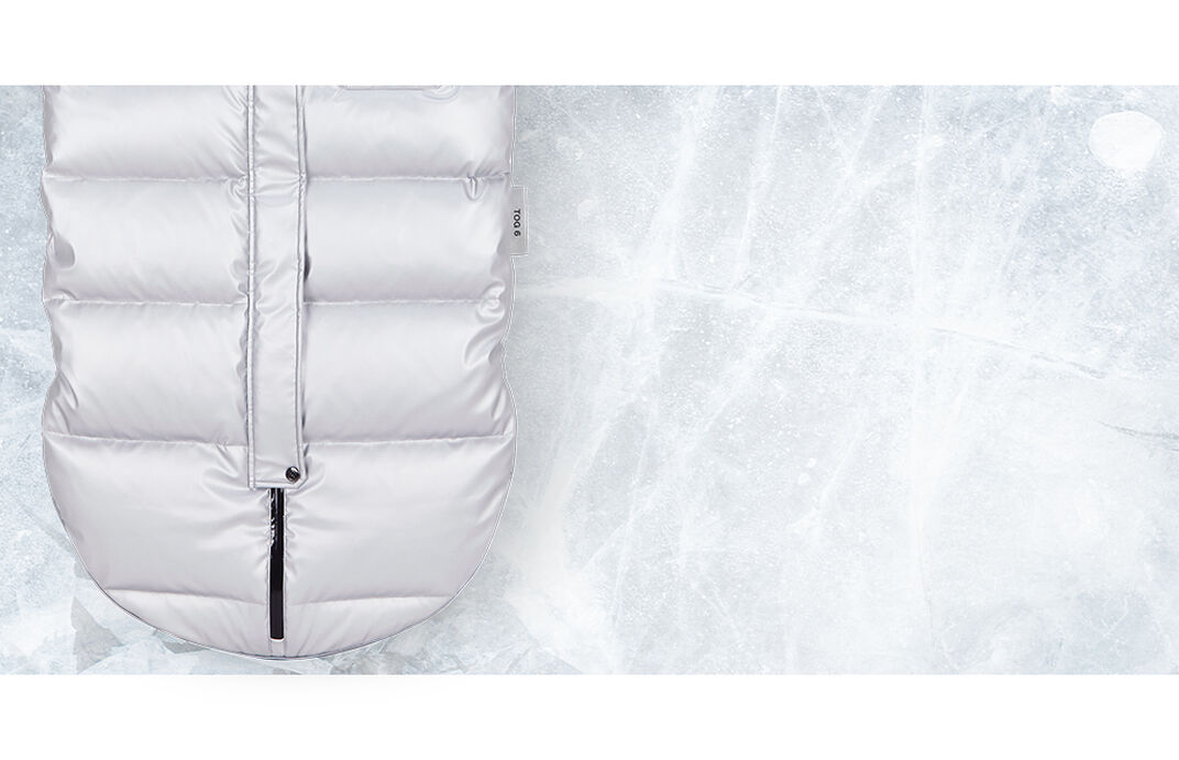 Ein silberner, gesteppten Winterfußsack auf einer eisigen Oberfläche.