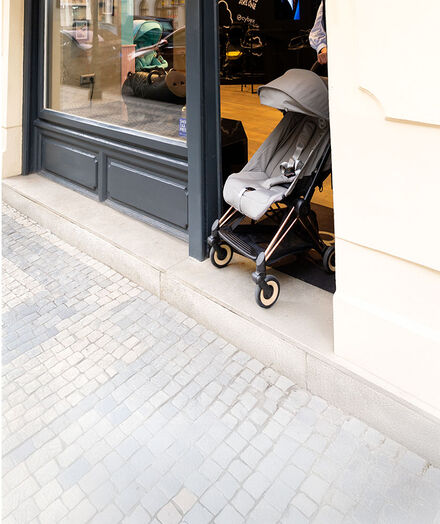 A CYBEX pushchair being pushed out of a store.