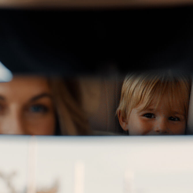 View into the rear mirror, showing direct eye contact between mother and child.