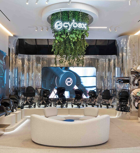 An assortment of CYBEX strollers and car seats. There's a bunch of vines hanging from the ceiling with a CYBEX logo at the front.