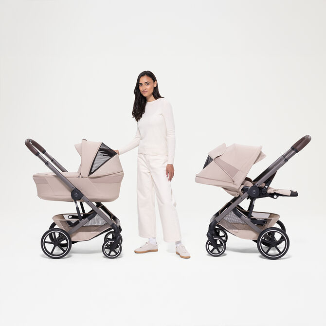 A woman standing next to two Balios S Lux strollers, showcasing the sun canopy of both.