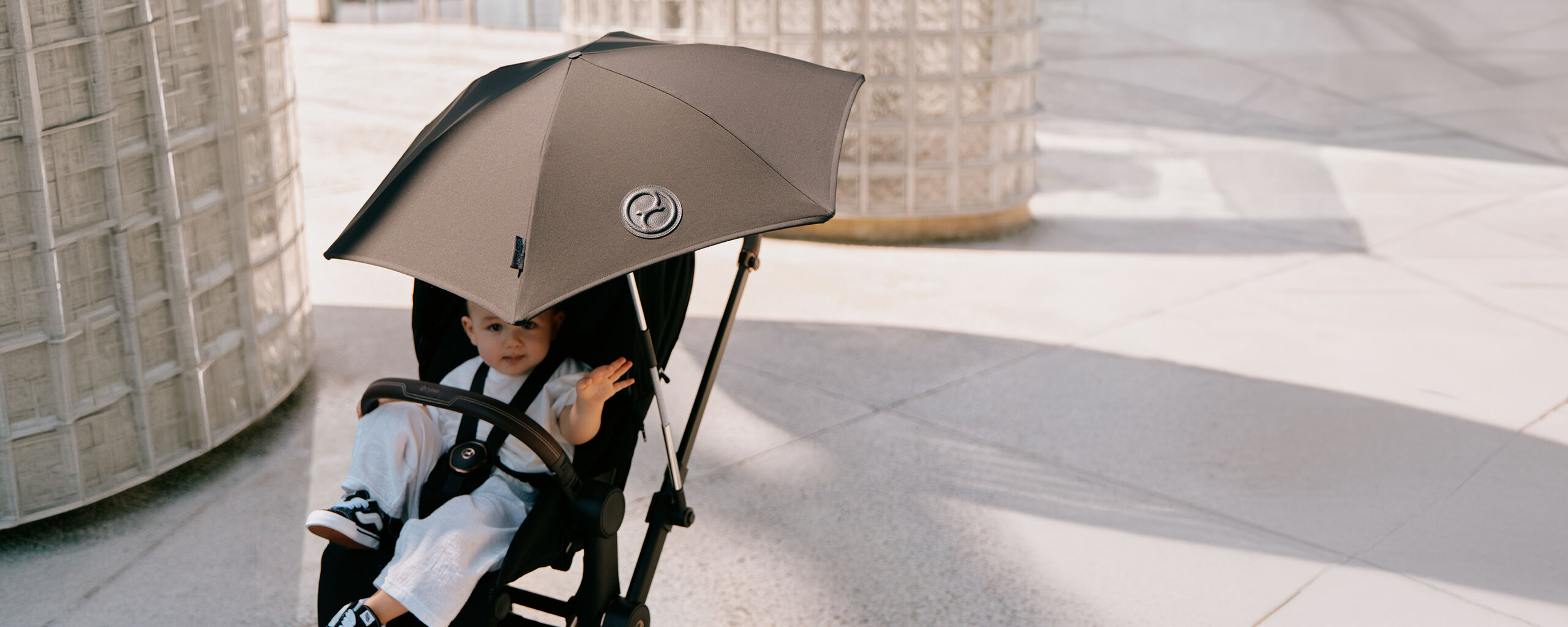 Un enfant dans une poussette CYBEX &eacute;quip&eacute;e d&rsquo;une ombrelle.