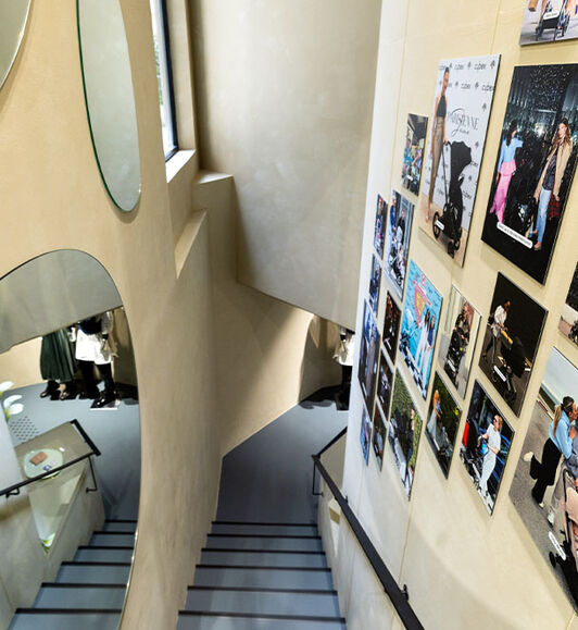 CYBEX store interior with a dramatic downward view along the staircase, featuring artistic photo installations on the walls.