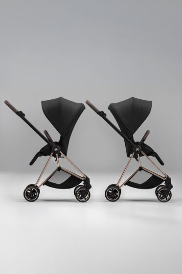 Two Priam strollers with seat units, one with a forward-facing position, one with a parent-facing one.