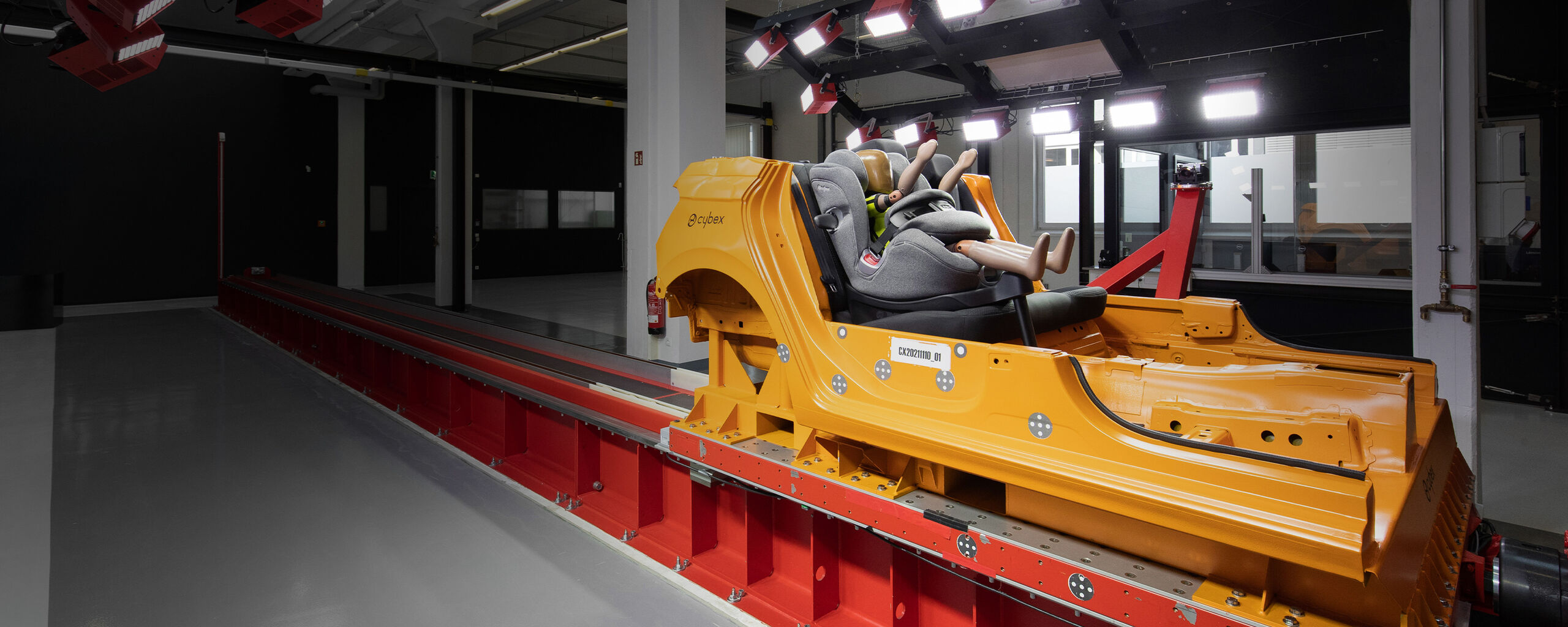En krocktestdocka sitter i en Cybex-bilbarnstol p&aring; en testbana i ett laboratorium.