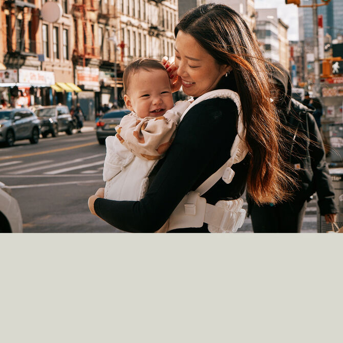 A mother holding her baby in a CYBEX baby carrier. It reads "500 Club Points".