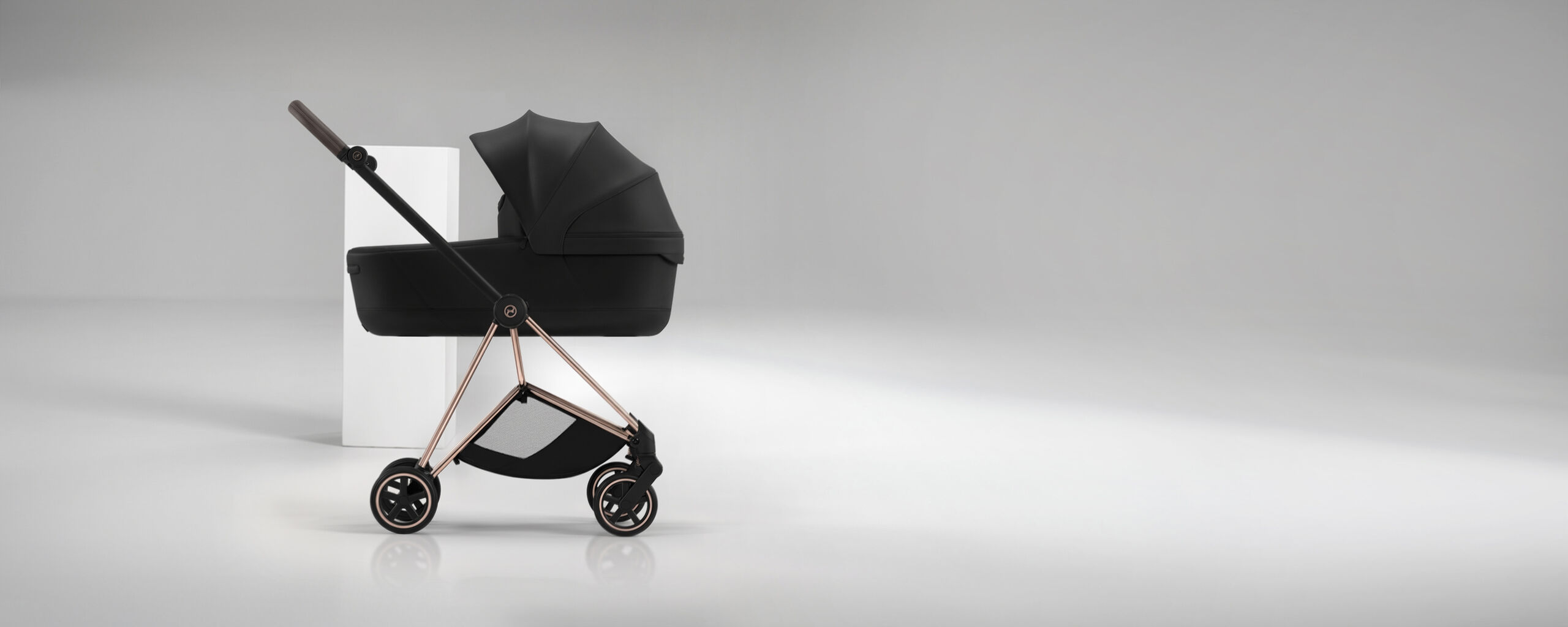 Ein Mios mit einer daran befestigten Fold Lux Carry Cot und einer wei&szlig;en S&auml;ule dahinter.