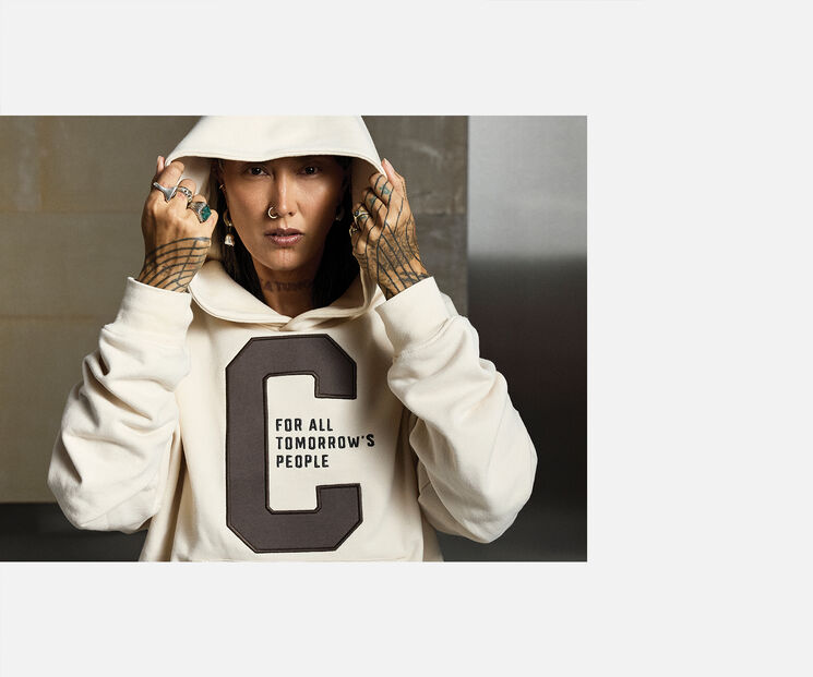 A young woman pulls down the hood of her CYBEX hoodie.
