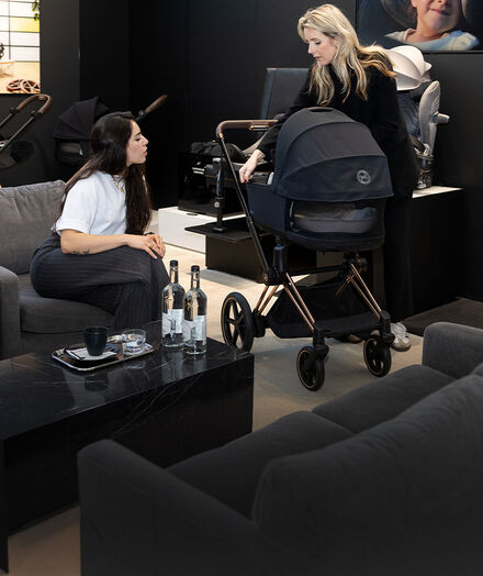 Twee vrouwen bespreken iets boven een CYBEX kinderwagen in de flagshipstore van CYBEX in Amsterdam.